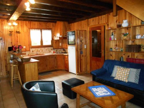 un salon avec un canapé bleu et une cuisine dans l'établissement Gîte de France Les acacias 3 épis - Gîte de France 4 personnes MAE-0044, à Eyrein