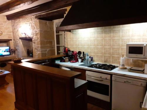a kitchen with a stove and a microwave at Gîte de France Le petit colibri 2 épis - Gîte de France 4 personnes MAE-9964 in Saint-Robert