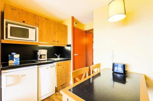 - une cuisine avec une table et un four micro-ondes dans l'établissement Résidence L'Ours Blanc - maeva Home - Studio 4 personnes - Confort MAE-9906, à Huez