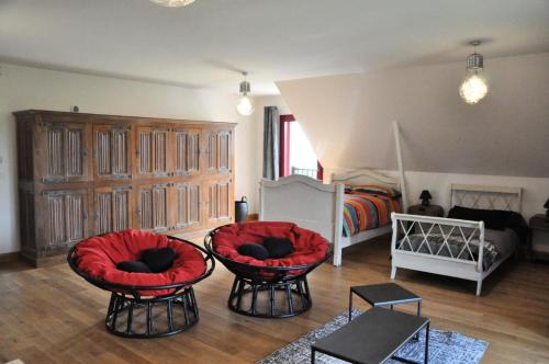 a living room with two red chairs and a bed at Gîte de France De chapdevialle la croisée des vents 4 épis - Gîte de France 12 personnes MAE-0064 in Juillac