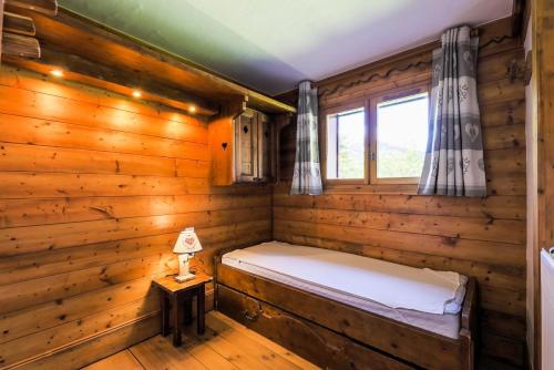 Dormitorio en cabaña de madera con cama y ventana en Résidence Les Fermes de Méribel - maeva Home - Appartement 3 pièces 5 pers 87 en Les Allues