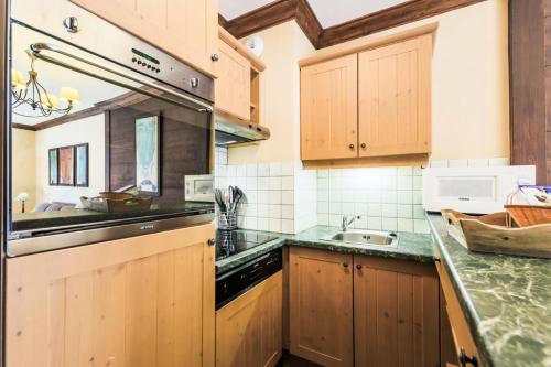 une cuisine avec des armoires en bois et un évier dans l'établissement Résidence Les Arcs 1950 Le Village - maeva Home - Appartement 2 pièces 4 personnes - Sélection MAE-3894, à Bourg-Saint-Maurice