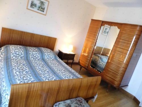 a bedroom with a wooden bed and a mirror at Gîte de France à Le Chastang 3 épis - Gîte de France 6 personnes MAE-0114 in Le Chastang