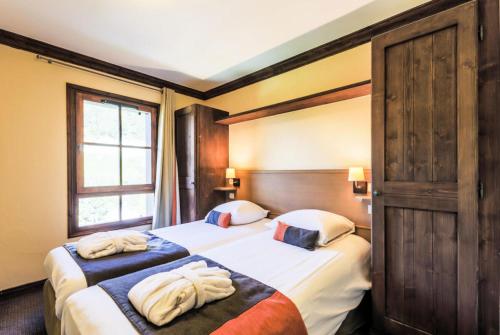 une chambre d'hôtel avec deux lits avec des serviettes dessus dans l'établissement Résidence Les Arcs 1950 Le Village - maeva Home - Appartement 3 pièces 6 personnes Sélection - Vue directe sur le Mont Blanc MAE-4037, à Bourg-Saint-Maurice