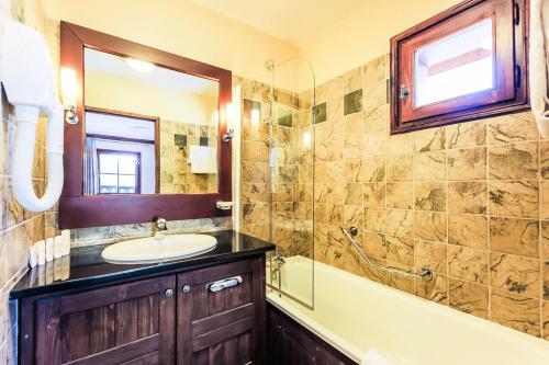 une salle de bain avec un lavabo, une baignoire et un miroir dans l'établissement Résidence Les Arcs 1950 Le Village - maeva Home - Appartement 3 pièces 6 personnes Sélection - Vue directe sur le Mont Blanc MAE-4037, à Bourg-Saint-Maurice