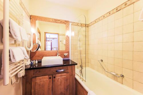 La salle de bains est pourvue d'un lavabo, d'une baignoire et d'un miroir. dans l'établissement Résidence Les Arcs Le Village - maeva Home - Appartement pièces Sélection 64, à Bourg-Saint-Maurice