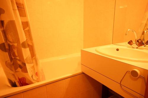 uma casa de banho com um lavatório e uma banheira em Résidence Michailles - Studio pour 4 Personnes 94 em Peisey-Nancroix