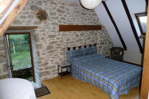 a bedroom with a bed and a stone wall at Gîte de France Tsa cabretaïre 3 épis - Gîte de France 6 personnes MAE-0194 in Saint-Bonnet-les-Tours-de-Merle