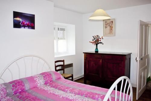 um quarto com uma cama rosa e um armário de madeira em Gîte de France à Benayes 3 épis - Gîte de France 6 personnes 204 em Benayes