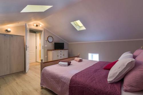 a bedroom with a large bed with a purple blanket at Villa La Musica by Istrialux in Čabrunići
