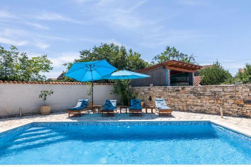 a swimming pool with two chairs and an umbrella at Villa La Musica by Istrialux in Čabrunići