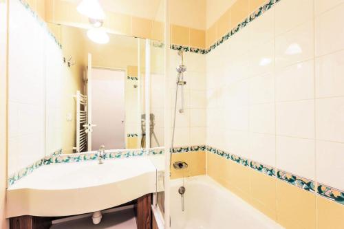 une salle de bain avec une baignoire, un lavabo et un miroir dans l'établissement Résidence Le Thabor - maeva Home - Appartement 2 Pièces 5 Personnes Confort MAE-5667, à Le Désert