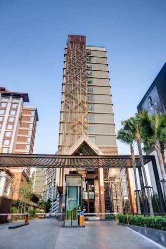 a tall building with palm trees in front of it at The Astra Bee friend in Chiang Mai