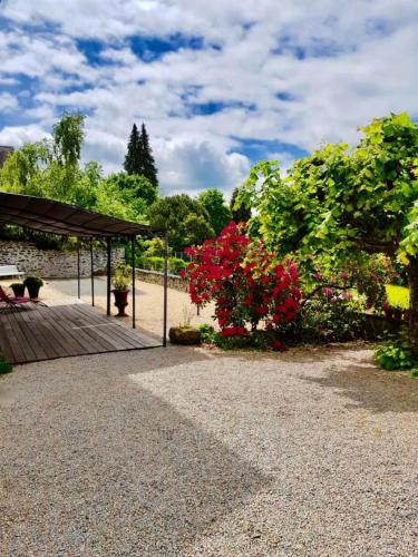 a garden with a wooden deck and red flowers at Gîte de France A perle de vue 4 épis - Gîte de France 14 personnes MAE-0294 in Uzerche