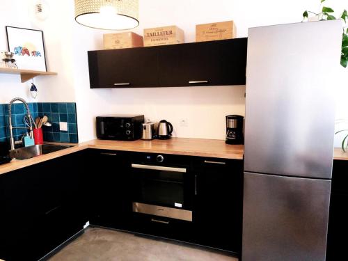 een keuken met zwarte kasten en een roestvrijstalen koelkast bij - Pièces 934 in Aix-les-Bains