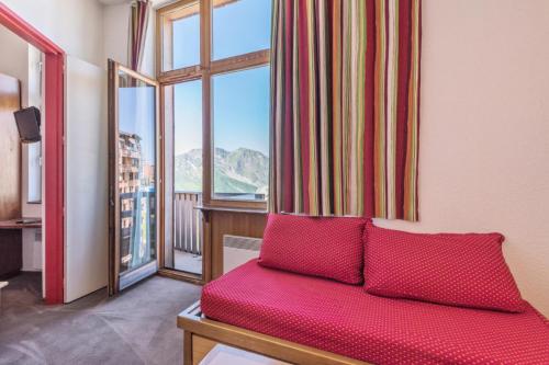 une chambre avec un canapé rouge en face d'une fenêtre dans l'établissement Résidence Les Fontaines Blanches - maeva Home - Appartement 2 pièces 5 personnes Confort MAE-2329, à Morzine