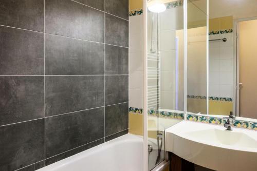 une salle de bain avec un lavabo, une baignoire et un miroir dans l'établissement Résidence Le Thabor - maeva Home - Appartement 3 pièces 7 personnes Confort MAE-2204, à Le Désert