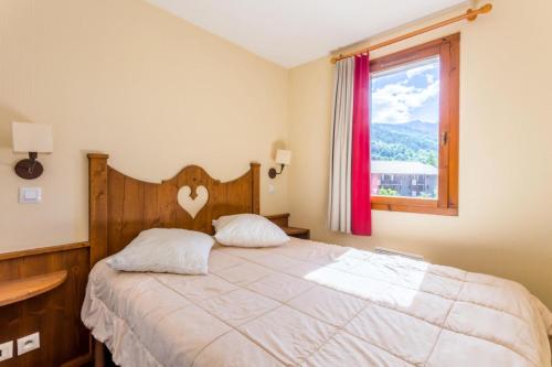 a bedroom with a bed with a wooden headboard and a window at Résidence L'Alpaga - maeva Home - Appartement 2 pièces 5 personnes Confort 39 in La Salle-les-Alpes