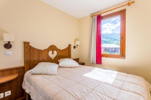 une chambre avec un lit avec une tête de lit en bois et une fenêtre dans l'établissement Résidence L'Alpaga - maeva Home - Appartement 2 pièces 5 personnes Confort MAE-4439, à La Salle Les Alpes