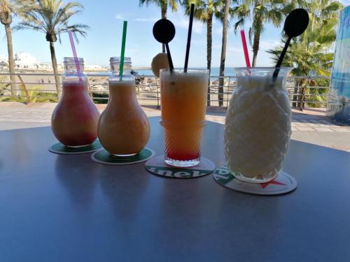 drie drankjes op een tafel met uitzicht op het strand bij Appartement moderne pour 6 adultes in Benalmádena