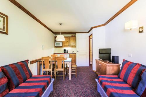 un salon avec un canapé et une table et une cuisine dans l'établissement Résidence La Marelle et Le Rami - maeva Home - Appartement 2 pièces 5 personnes Sélection MAE-6258, à La Plagne Tarentaise