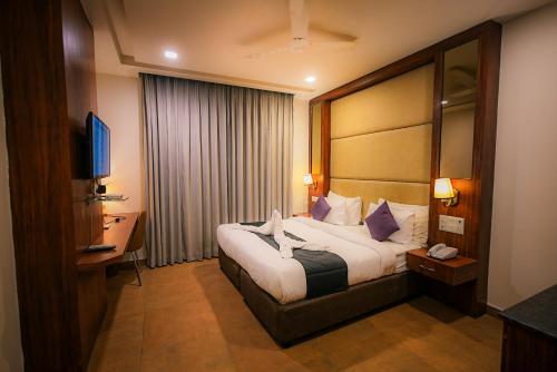 um quarto de hotel com uma cama e uma televisão em Dazzling em Agra