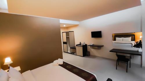 JTS Hotel في Sinabono: غرفة نوم بسرير ومكتب ومرآة