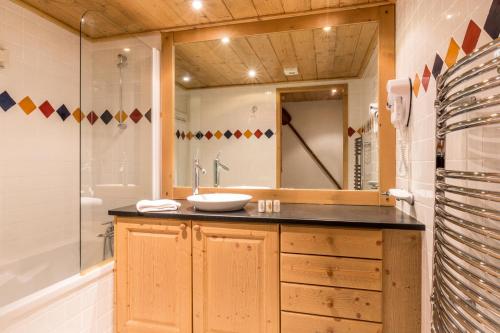 ein Badezimmer mit einem Waschbecken und einem großen Spiegel in der Unterkunft Les Chalets du Gypse - Appartement CHALETS GYPSE B02 pour 8 Personnes 24 in Saint-Martin-de-Belleville