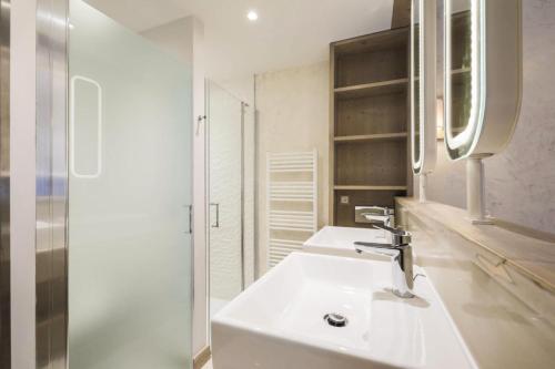 a white bathroom with two sinks and a mirror at Résidence Premium L'Hévana - maeva Home - Appartement 3 pièces 6 personnes 67 in Les Allues