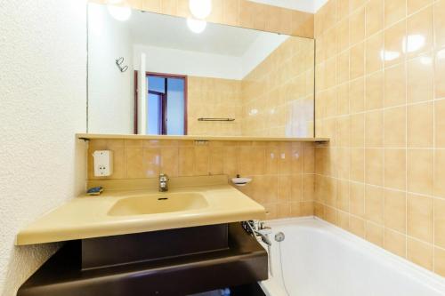 La salle de bains est pourvue d'un lavabo, d'un miroir et d'une baignoire. dans l'établissement L'Aiguille - maeva Home - Appartement 2 pièces 5 personnes Confort 19, à Chamonix-Mont-Blanc