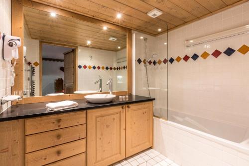 een badkamer met een wastafel, een bad en een spiegel bij Les Chalets du Gypse - Appartement CHALET GYPSE B01 pour 8 Personnes 23 in Saint-Martin-de-Belleville