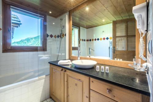 a bathroom with a sink and a tub and a mirror at Les Chalets du Gypse - Appartement CHALET GYPSE C02 pour 8 Personnes 30 in Saint-Martin-de-Belleville