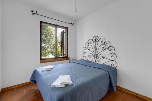Un dormitorio con una cama azul con toallas. en Villa due Archi, en S'Archittu