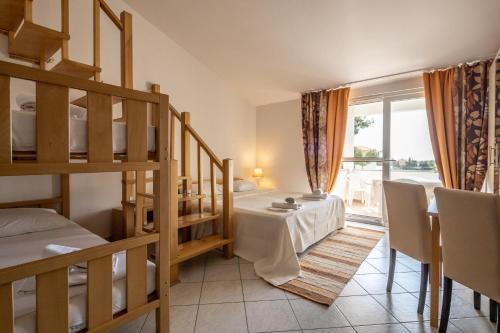 a room with two bunk beds and a table and chairs at Apartments Eddy Veselica in Novalja