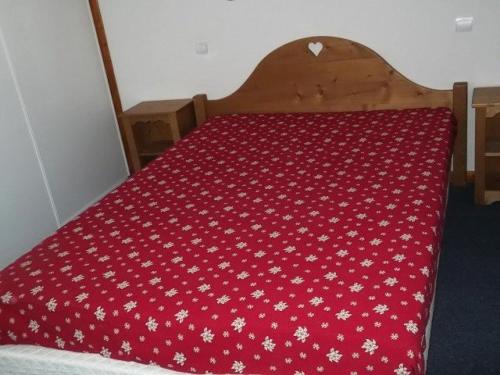 Una cama con colcha roja con flores blancas. en Résidence BALCONS DU SOLEIL - 3 Pièces pour 6 Personnes 304, en Orcières