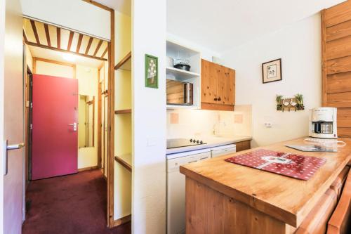 une cuisine avec un comptoir et une porte rouge dans l'établissement Quartier La Forêt - maeva Home - Appartement 2 pièces 5 personnes Sélection MAE-8884, à Valmorel
