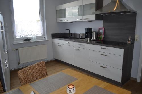 a kitchen with white cabinets and a black refrigerator at Ferienwohnung Edelweiss in Bad Wilsnack
