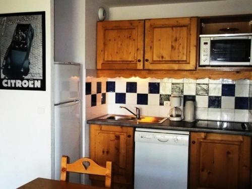 une cuisine avec des armoires en bois et un réfrigérateur blanc dans l'établissement Résidence Balcons Du Soleil - TROIS PIECES 7 pers - RESIDENCE BALCONS DU SOLEIL n° 313 MAE-7434, à Orcières