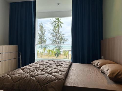a bedroom with a bed and a large window at Beachfront Retreats @RoxyBeachSematanApt. in Sematan