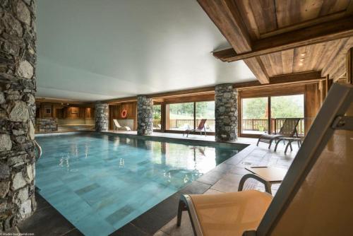 a swimming pool in a house with a stone wall at Les Chalets du Gypse - Appartement CHALET GYPSE A03 pour 6 Personnes 44 in Saint-Martin-de-Belleville