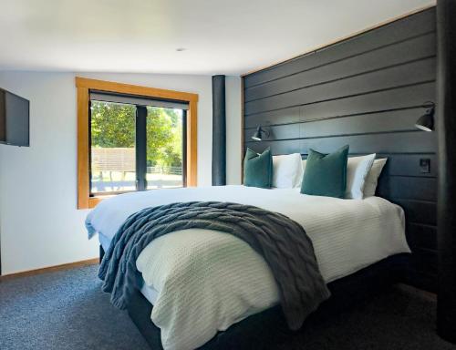 Un dormitorio con una cama grande y una ventana en Black Cottage Boutique Acommodation, en Havelock North