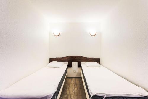 two beds in a room with white walls and wooden floors at Résidence Les Bergers - maeva Home - Studio 4 personnes - Sélection 34 in LʼHuez