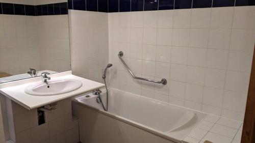 ein weißes Badezimmer mit einem Waschbecken und einer Badewanne in der Unterkunft Résidence BALCONS DU SOLEIL - 2 Pièces pour 4 Personnes 504 in Orcières
