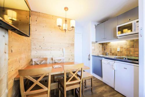 une cuisine et une salle à manger avec une table et des chaises en bois dans l'établissement Résidence Les Constellations - maeva Home - Appartement 2 Pièces 5 Personnes - Selection MAE-0341, à La Plagne Tarentaise