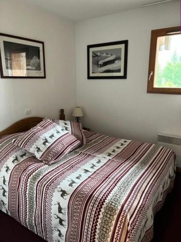 un lit dans une chambre avec deux tableaux au mur dans l'établissement Résidence Les Cristallines - TROIS PIECES 6 PERS N°001 LES CRISTALINES AVEC TERRASSE et parking MAE-8114, à Orcières