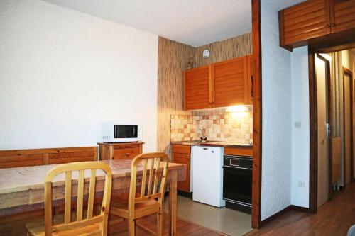 une cuisine avec des armoires en bois et une table et des chaises dans l'établissement Résidence Orr Des Forets - 32 Orrianes des Forets MAE-0504, aux Orres