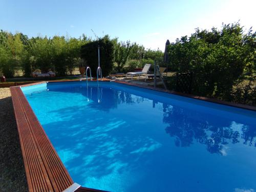une grande piscine bleue entourée d'un banc en bois dans l'établissement Le Mas du Ruisseau, à Bellegarde
