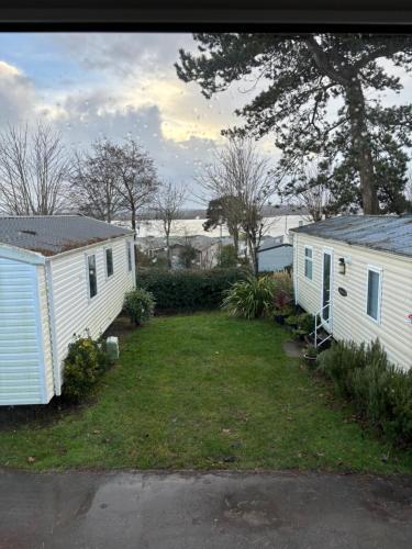 two white mobile homes in a yard with trees at JUANI in Lytchett Minster