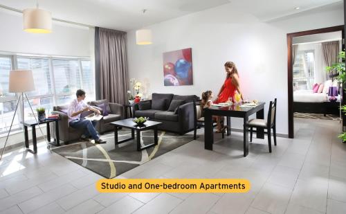 Citadines Metro Central Hotel Apartments في دبي: رجل وامرأة يجلسون في غرفة المعيشة