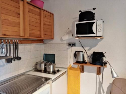 une cuisine avec un micro-ondes et une cuisinière dans l'établissement Résidence L'eperviere - Studio à deux pas du centre MAE-0754, aux Orres